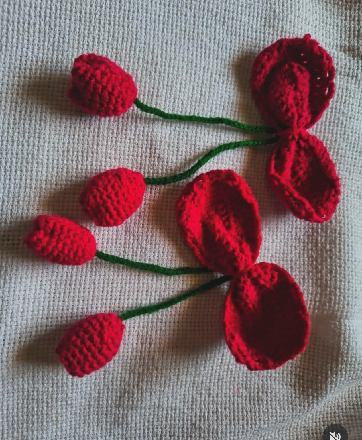 Set of hand-crocheted red tulips and open blossom petals on flexible green stems